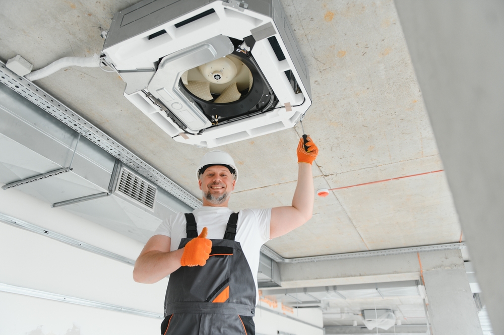 HVAC technician performing annual AC maintenance to improve energy efficiency and lower utility bills